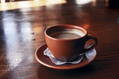 Taze Americano kahvesi. Sütlü, geleneksel kahverengi kilden bardakta, ahşap masada.