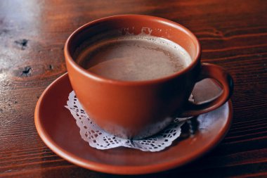 Taze Americano kahvesi. Sütlü, geleneksel kahverengi kilden bardakta, ahşap masada.