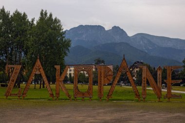 Zakopane, Polonya - 1 Ağustos 2024: Tahta harfler - kentin adını taşıyan simge işareti. Arka planda Yüksek Tatra Dağları 'nın panoramik manzarası zirveleri ve Giewont. 