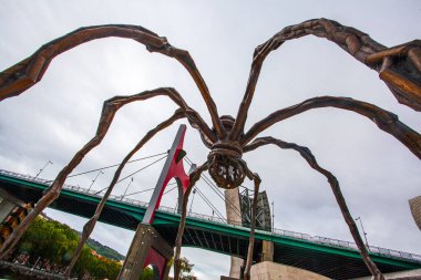 Bilbao, İspanya - 15 Temmuz 2024: Louise Bourgeois 'in Guggenheim Müzesi' ndeki heykeli ve La Salve nehri üzerindeki ünlü köprüsü 