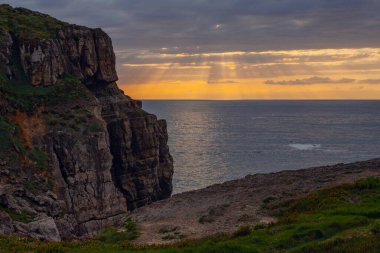 Cantabria, İspanya 'daki Atlantik denizinde güzel bulutlar ve ışınlarla gün batımı