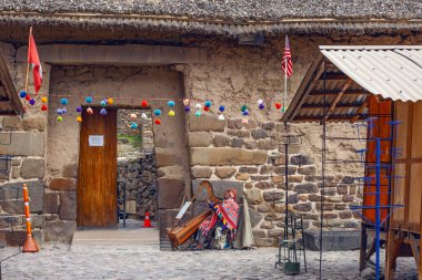 Ollantaytambo, Peru - 5 Mayıs 2022: Geleneksel elbiseli Inka adam, Ollantaytambo antik şehir kalesinin girişinde arpta müzik çalıyor