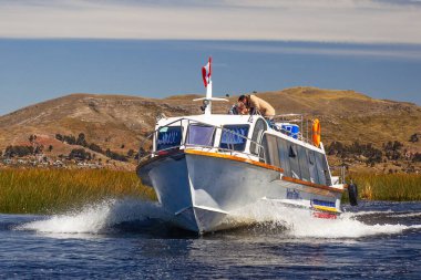 Peru, Titicaca Gölü. - 29 Nisan 2022: Uros adası turları ile motorlu tekne güneşli bir günde kamış adalarından geçiyor..