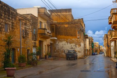 Gozo, Malta - 16 Şubat 2024: Günbatımında Gozo Adası 'ndaki bir kasabanın sokaklarındaki geleneksel taş binalar