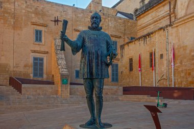 Valletta, Malta - February 13, 2024: Bronze statue of Grand Master Jean Parisot  de Vallette, in Pjazza Jean de Vallette, with Our Lady of Victories Chapel behind, clipart