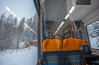 Poprad, Slovakya - 16 Aralık 2024: Modern elektrikli trenin vagonundan Slovakya 'daki Strbske Pleso' ya giden Tatres dağlarına bakın.