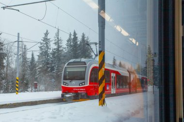 Strbske Pleso, Slovakya - 16 Aralık 2024: Slovakya 'daki Strbske Pleso' nun karlı tren istasyonunda yolcuları bekleyen modern elektrikli tren dağ parkı High Tatras 'ta..