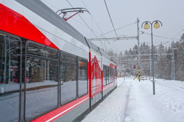 Strbske Pleso, Slovakya - 16 Aralık 2024: Slovakya 'daki Strbske Pleso' nun karlı tren istasyonunda yolcuları bekleyen modern elektrikli tren dağ parkı High Tatras 'ta..