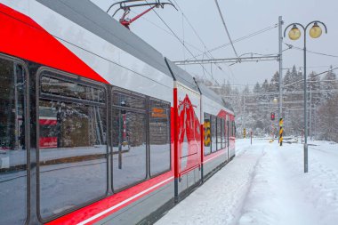 Strbske Pleso, Slovakya - 16 Aralık 2024: Slovakya 'daki Strbske Pleso' nun karlı tren istasyonunda yolcuları bekleyen modern elektrikli tren dağ parkı High Tatras 'ta..