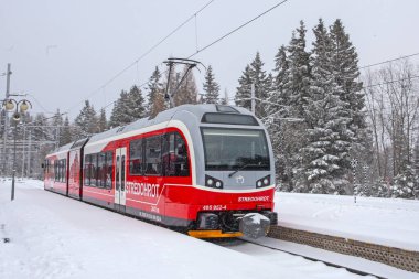 Strbske Pleso, Slovakya - 16 Aralık 2024: Slovakya 'daki Strbske Pleso' nun karlı tren istasyonunda yolcuları bekleyen modern elektrikli tren dağ parkı High Tatras 'ta..