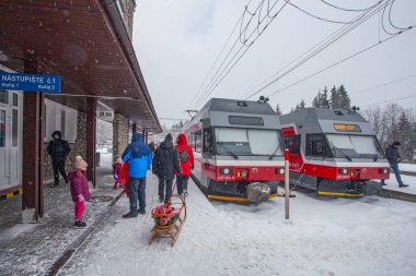 Strbske Pleso, Slovakya - 16 Aralık 2024: Slovakya 'daki Strbske Pleso' nun karlı tren istasyonunda yolcuları bekleyen modern elektrikli tren dağ parkı High Tatras 'ta..