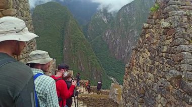 Machu Picchu, Peru - 12 Mayıs 2022: Machu Picchu antik kentini bulutlu havada ziyaret eden turistler