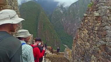 Machu Picchu, Peru - 12 Mayıs 2022: Machu Picchu antik kentini bulutlu havada ziyaret eden turistler