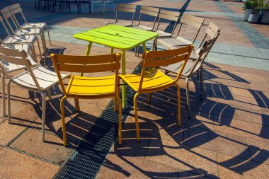 Güneşli değirmende gölgeli renkli metal sandalyeler 