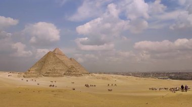 Giza, Mısır - 9 Mart 2025: Mısır 'daki Giza Piramit Kompleksi, çölden turistle piramitlerin etrafında bir deve gezisi manzarası