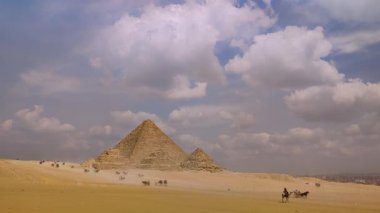 Giza, Mısır - 9 Mart 2025: Mısır 'daki Giza Piramit Kompleksi, çölden turistle piramitlerin etrafında bir deve gezisi manzarası
