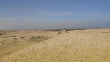 Giza, Mısır - 9 Mart 2025: Mısır 'daki Giza Piramit Kompleksi, çölden turistle piramitlerin etrafında bir deve gezisi manzarası.