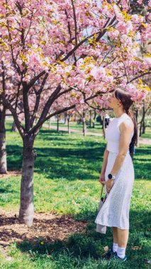 Kyiv 'deki Sakura bahçe parkında beyaz elbiseli güzel bir kadın.