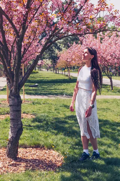 Kyiv 'deki Sakura bahçe parkında beyaz elbiseli güzel bir kadın.
