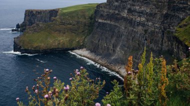 İrlanda 'daki Moher Kayalıkları' nın engebeli kıyı şeridi ve bulutlu gökyüzü manzarası