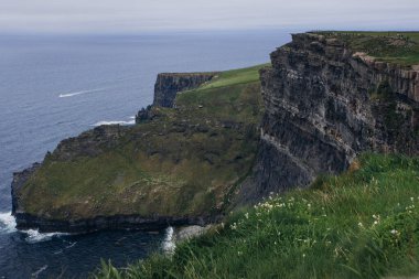 İrlanda 'daki Moher Kayalıkları' nın engebeli kıyı şeridi ve bulutlu gökyüzü manzarası