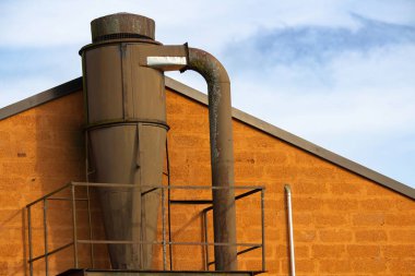 Turuncu duvarda mavi gökyüzüne karşı kereste fabrikası sanayi filtresi.