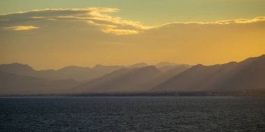 İspanyol sahil şeridi üzerinde renkli gün batımı. Akşam güneş ışınları ile deniz manzarası. Costa dorada resort.