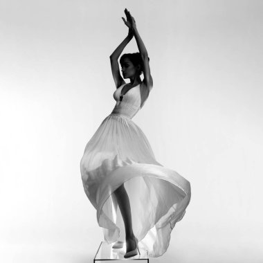 Güzel genç bayan şık bir elbise içinde fotoğraf stüdyosunda poz veriyor. Parlak renkli spot ışıklarıyla seksi bir model. Beyaz gelinlik giymiş bir kadının portresi. Sanat fotoğrafçılığı.