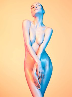 Bir fotoğraf stüdyosundaki profesyonel bir modelin fotoğrafçılığı. Arka planda renkli neon ışıklar var. Gece kulübünde dans eden bir kadın. Çıplak bir mankenin güzel vücudu.