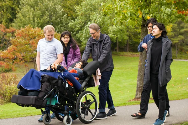 春天或秋天的阴天 多种族家庭和坐在轮椅上的小男孩在公园散步 — 图库照片