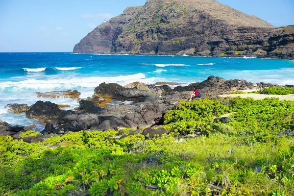 夏威夷瓦胡岛Makapu U海滩 一名女性坐在岩石海岸边 免版税图库图片