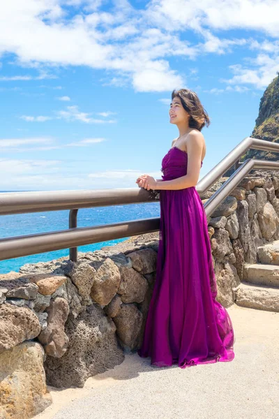 ハワイ オアフ島のマカプのビーチとハワイの海を見下ろすマカプのビューポイントに立っている正式な紫色のドレスの若い女性 — ストック写真