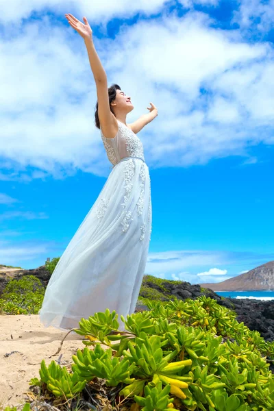 夏威夷海岸 身穿白衣的少女举起双臂 在户外赞美她 图库图片