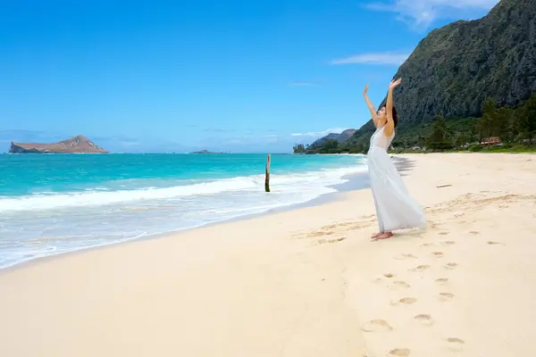 穿着白色衣服的少女 头戴夏威夷假发 双臂高高地敬拜或感受着海风 免版税图库图片