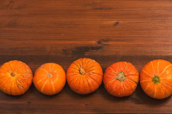 素朴な木の背景の上に秋のオレンジのハロウィンカボチャ コンセプト ハロウィーンのお祝いの背景 秋の収穫 ミニマリズムの休日の装飾のテンプレート トップビュー フラットレイ コピースペース — ストック写真