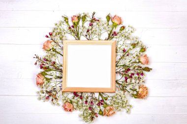 Beyaz kırsal ahşap bir masa üzerinde dalların ve çiçeklerin düzleştirilmesi büyüleyici ve doğal bir kompozisyon oluşturur.