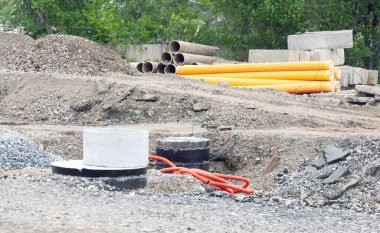 Su ve kanalizasyon için güçlendirilmiş beton kuyusu. Yığınla moloz ve inşaat malzemesi olan bir inşaat alanı.