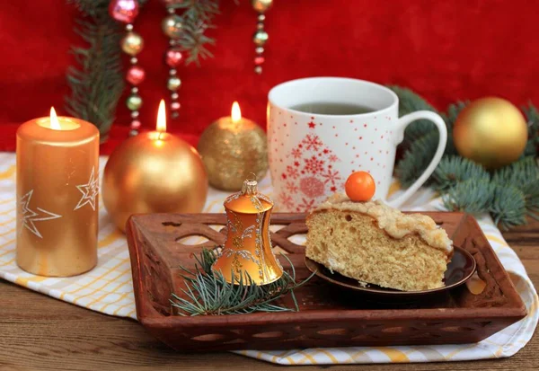 圣诞茶 一大杯香草茶和酵母蛋糕加山莓角 金色蜡烛 针叶树枝条和红色背景的灌木的假日装饰 — 图库照片