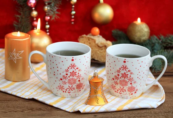 两个人的圣诞茶一大杯草药茶金色蜡烛 针叶树枝条和红色背景的灌木的假日装饰 — 图库照片
