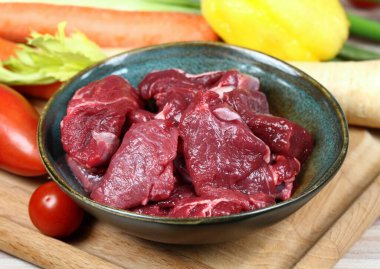 Geyik yahnisi ya da gulaş için çiğ geyik eti. İçinde geyik eti parçaları olan bir kase. Yemek pişirmek için taze sebze..