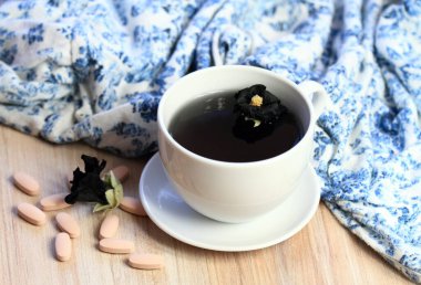 Herbal tea from flower of  Alcea rosea Nigra, known as Black hollyhock used as medicinal herb and vitamins. Focused on flower head in the cup of tea.  It is used in traditional herbal medicine. 