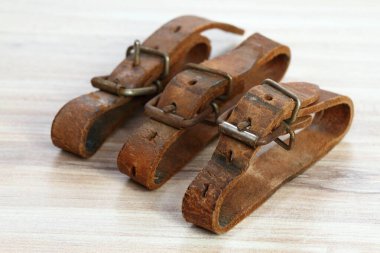Eski deri kayaklar kayak takımlarını birbirine bağlardı. Ahşap masada doğal deri kemerler.. 