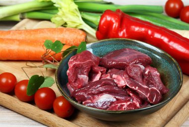 Geyik yahnisi ya da gulaş için çiğ geyik eti. İçinde geyik eti parçaları olan bir kase. Yemek pişirmek için taze sebze..