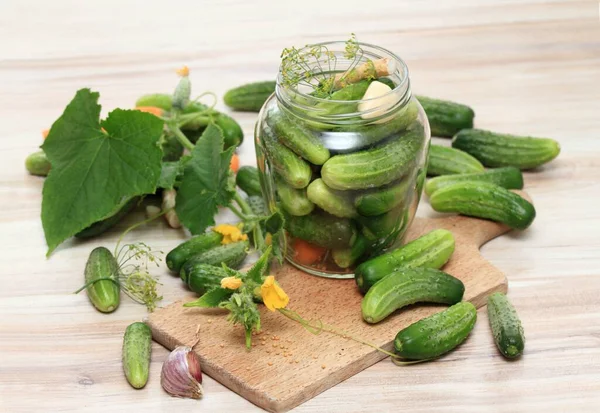 Preparing preserved pickled cucumbers in spicy brine. Fresh pickle cucumbers, carrot, dill, garlic and  on wooden table.