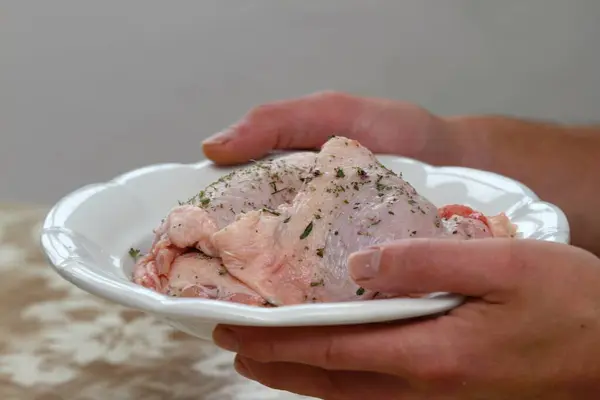 Man\'s hands and raw chicken meat. Man\'s hands and raw chicken meat. Young cook holding plate with marinated white meat.
