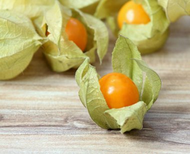 Tahta masadaki kabuklu Physalis Peruviana meyvesi. Aynı zamanda Bektaşi Burnu, kiraz ezmesi ya da kış kirazı olarak da bilinir..