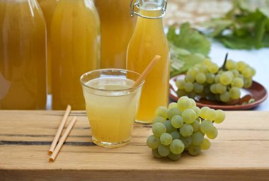Şişede ev yapımı beyaz üzüm şurubu ve bardakta üzüm suyu. Taze aromatik organik beyaz üzüm ve bal veya şekerden yapılır..