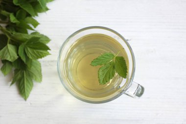 Aegopodyum podagraria 'dan bitkisel çay, beyaz ahşap masada genellikle yaşlı ya da piskopos otu olarak bilinir. Geleneksel ilaçlarda acı veren eklemler için kullanılan bitki çayı, taze yapraklar, düz yatak..