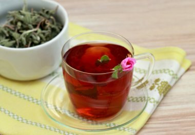 Kaya gülü olarak bilinen Cistus incanus 'tan bir fincan bitkisel karışım. Birçok iç ve dış faydası olan geleneksel bitki çayı. Çayın içinde pembe bir gül tomurcuğu..