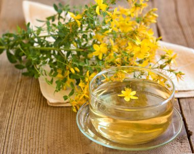 Hypericum Performans Perforatum 'dan alınmış bitkisel çay, yaygın olarak St John Wort olarak bilinir. Tahta masada taze çiçeklerle iç. Geleneksel bitkisel ilaçlar.